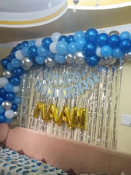 A simple backdrop for a home celebration. I created a balloon arch in shades of blue and silver over a tinsel curtain, with the birthday boy's name in gold foil letters.