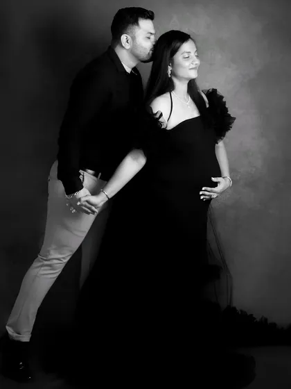 Black and white photography adds a classic, dramatic touch. This full-length portrait of a couple in coordinated black outfits emphasizes their bond and the beautiful silhouette of the baby bump.