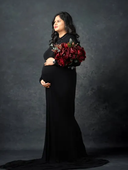 A classic and elegant portrait in a simple black gown. The addition of a deep red bouquet adds a touch of color and sophistication to this timeless maternity photo.