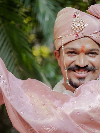 A close-up portrait of the groom, smiling and looking dapper in his wedding attire.