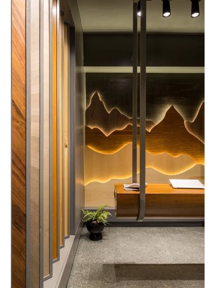 A close-up of the suspended veneer desk, which appears to float in front of the backlit, mountain-scape art piece.