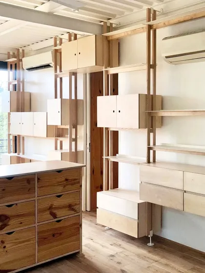 This modular shelving system in a Sarvapriya Vihar residence is an example of furniture as spatial planning. The open-backed plywood and wood units create storage and display areas while maintaining a sense of lightness and connection between different zones of the room.