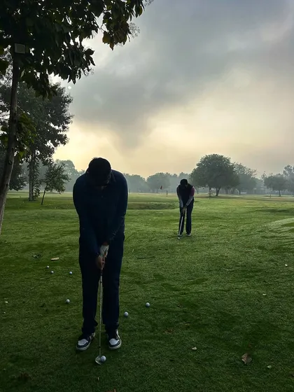 Two golfers practice their chipping in the early morning mist, dedicated to improving their game.