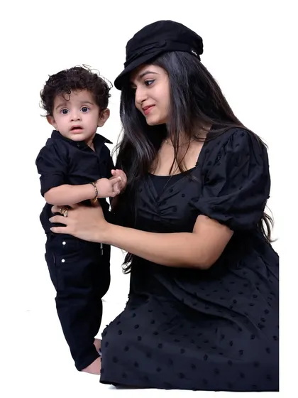A mother and her young son in matching black outfits. The studio setting allows for clean, focused portraits that highlight your connection without any distractions.