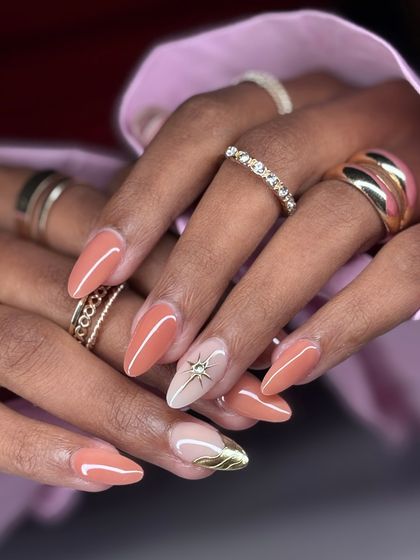 A lovely peach-colored manicure with a sparkling accent nail. The accent features a hand-painted star with a rhinestone center and a sculpted gold detail.