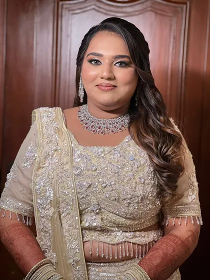A glamorous reception look with smokey eyes and soft waves. The bride is wearing a heavily embellished off-white lehenga.