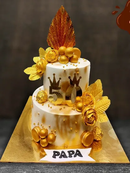 A grand celebration for a grand man. This two-tier golden jubilee cake was designed for a 50th birthday, featuring elegant gold accents, crowns, and a "Papa" banner to honor the special milestone.