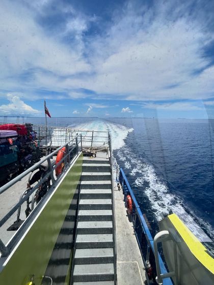The view from the back of the ferry, leaving a white wake in the vast blue ocean.