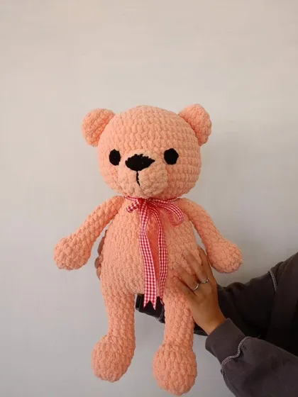 Holding up the handmade pink teddy bear to show its size and cuddly shape.