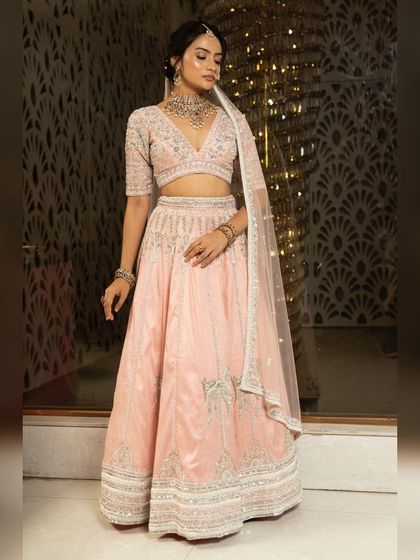 Twirl into a fairytale with this baby pink bridal lehenga. I designed it with intricate horse embroidery on the raw silk skirt and paired it with a heavily handworked blouse and a delicate net dupatta for a truly heavenly look.