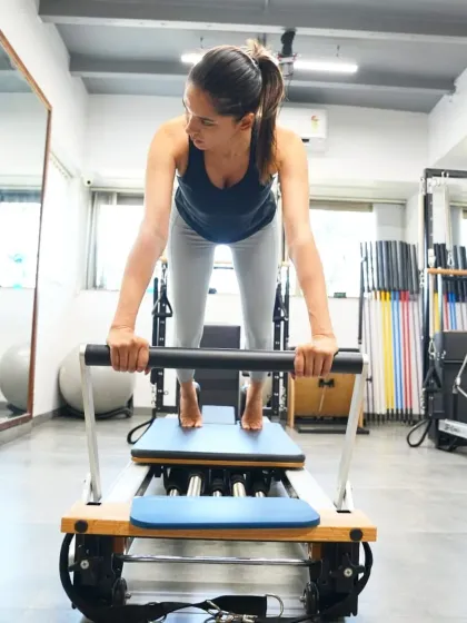 A client demonstrates a powerful move on the reformer. This machine uses spring resistance to lengthen and strengthen muscles simultaneously, helping you redefine your body's limits.
