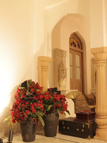 A corner of the Sangeet venue, styled with vintage elements like a gramophone and a trunk, alongside lush red floral arrangements, adding to the timeless theme.