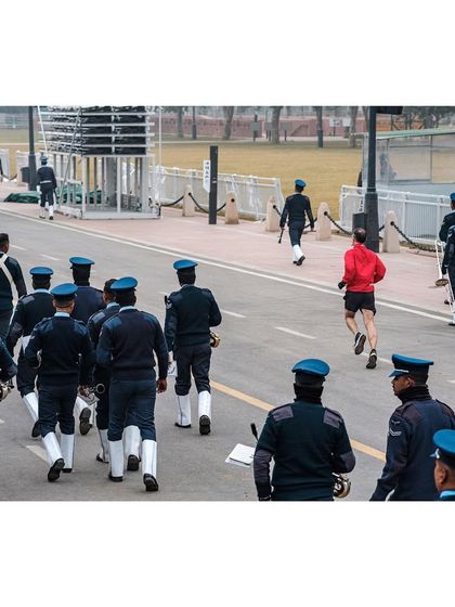 A civilian in a red jacket runs alongside the Indian Air Force band during a Republic Day parade rehearsal. It's a quirky, candid moment showing the intersection of civilian life and national ceremony.