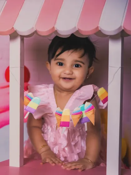 A close-up of a happy baby enjoying the candy cart. The colorful ice cream garland adds a festive touch.