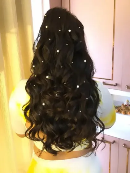 A beautiful shot of the half-up hairstyle with scattered pearls, a lovely choice for a pre-wedding event.