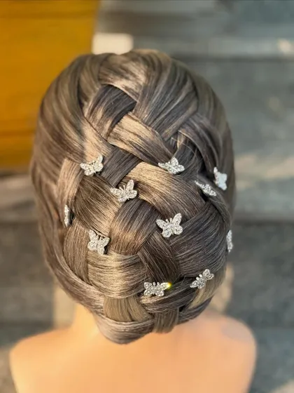 Mastering intricate techniques like this basket-weave updo is a core part of our advanced hairstyling course. We teach our students how to create clean, complex patterns and accessorize them with delicate details like these butterfly pins for a whimsical touch.