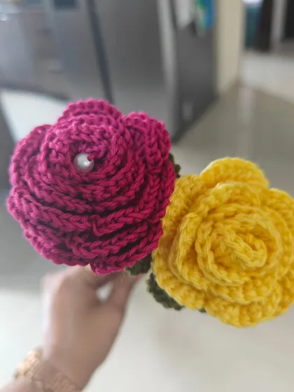 A close-up of the magenta and yellow crochet roses, showcasing the detailed petal work and the lovely texture of the cotton yarn.