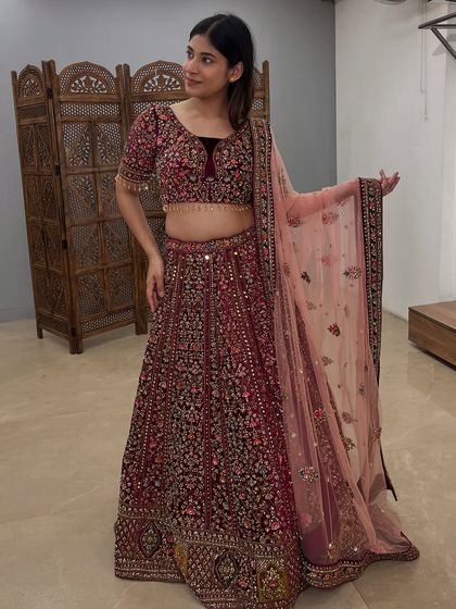 A full-length shot showcasing the elegant drape and flow of this beautiful maroon bridal lehenga.