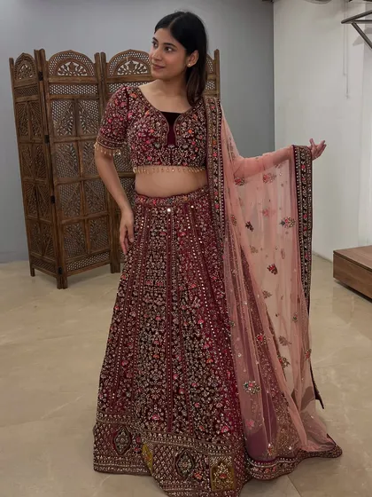 A full-length shot showcasing the elegant drape and flow of this beautiful maroon bridal lehenga.
