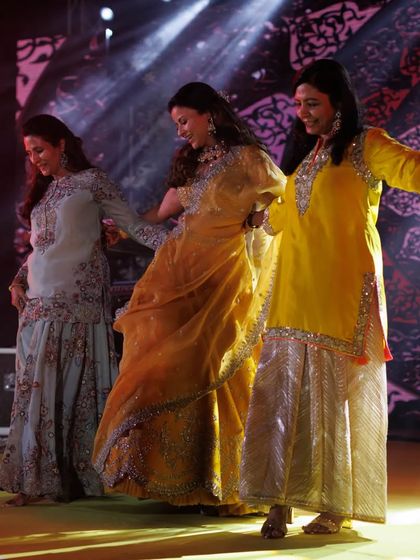 The ladies of the family in a graceful, flowing dance move. Their coordinated outfits look beautiful together.