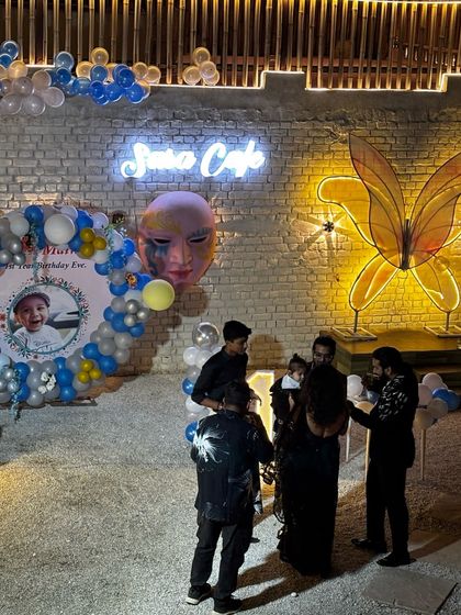 A wide view of a first birthday setup. You can see the custom photo backdrop, balloon decorations, and our signature neon butterfly wall art.