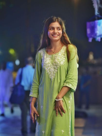 A lovely candid portrait with a genuine, happy smile. The blurred background of the night market adds a vibrant and lively feel to the shot.