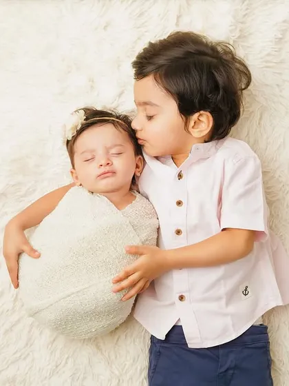 A big brother gives his new sibling a gentle kiss on the forehead. This is a moment of pure, innocent love that parents will cherish.