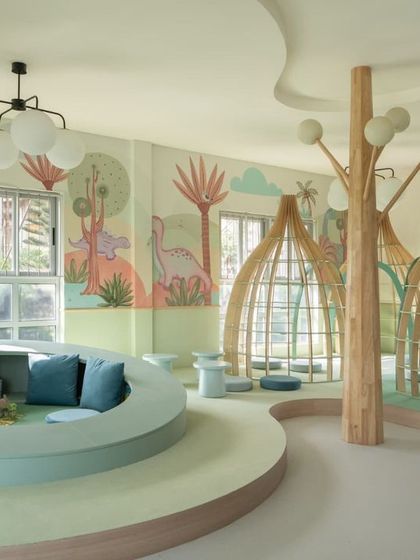 A panoramic view of the nursery library, showcasing the sunken reading pit with plush cushions, the whimsical reading pods, and the gentle, flowing forms that define the space. It’s a true sanctuary for young readers.