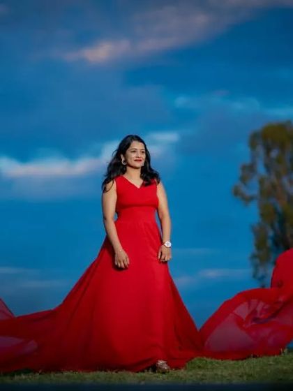 A stunning solo portrait of the bride-to-be in a red flying gown. The wind catches the fabric, creating a powerful and dramatic image against the evening sky.