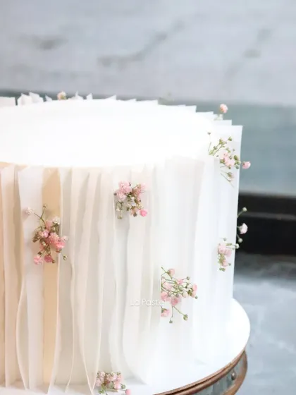 A close-up of the wafer paper draping technique. Here, I've tucked in tiny sprigs of pink baby's breath to add a soft pop of color to the all-white design.