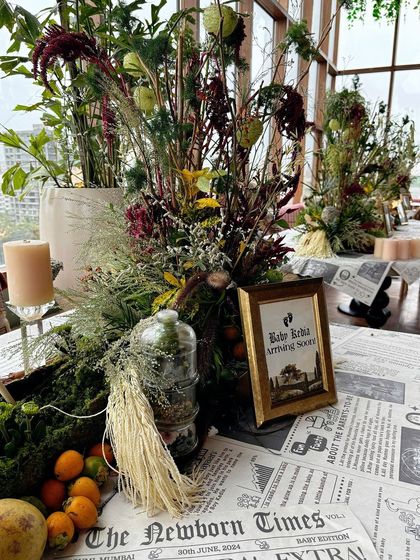 The tables are decorated with custom 'The Newborn Times' newspaper placemats and wild, rustic floral arrangements.