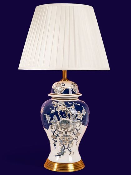 A classic ginger jar table lamp with a deep blue base and intricate gold floral detailing. Paired with a simple pleated shade, it's a sophisticated lighting choice for any traditional or transitional decor.