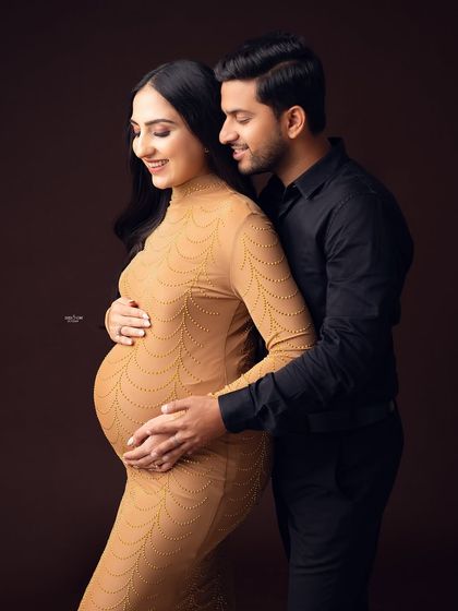 A classic and elegant couple's portrait. The warm, earthy tones of the background and the mamma's dress create a cozy and intimate feel.