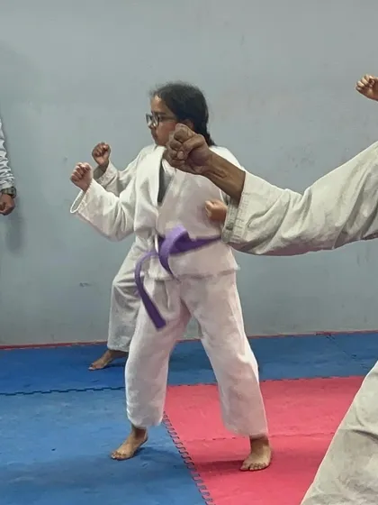 A student with a purple belt performing a block during her exam. Each belt represents a new level of skill and understanding.