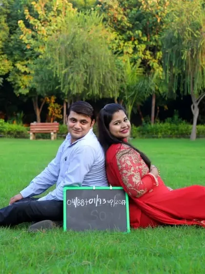 A wide shot of an expecting couple relaxing in a park. We can incorporate dates or messages on a chalkboard for a personal touch.