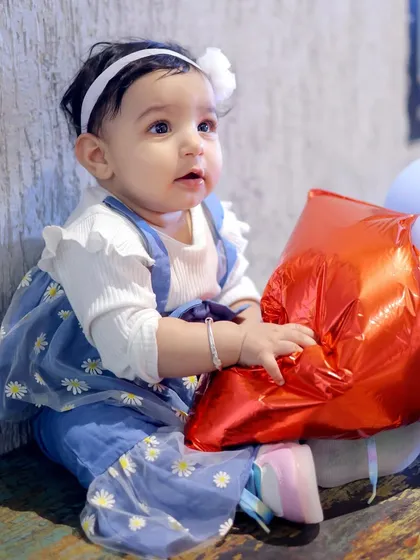 An innocent, curious expression captured in a close-up portrait of a baby girl at her birthday celebration. Kids' photography is about capturing their many moods.