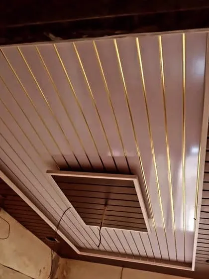 A clean PVC panel ceiling with a wood-finish border and a recessed central section. This design is perfect for adding a touch of modern warmth to a room.