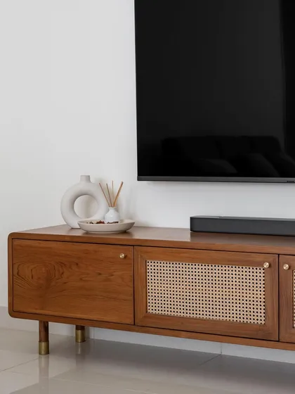 Our 'Marshall' TV unit combines solid wood and rattan shutters. The design integrates the line's signature curved edges, brass knobs, and sturdy legs for a timeless look.