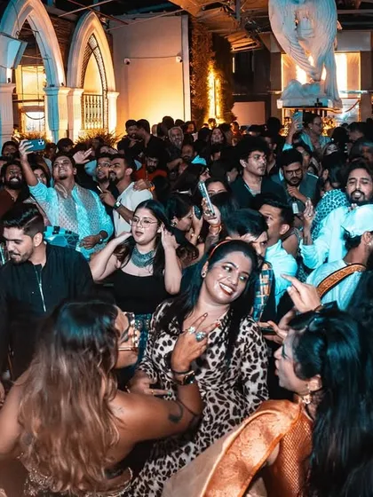 A wide shot of the dance floor during the Diwali party. You can see everyone dressed in their festive best, enjoying the fusion of fashion and music.