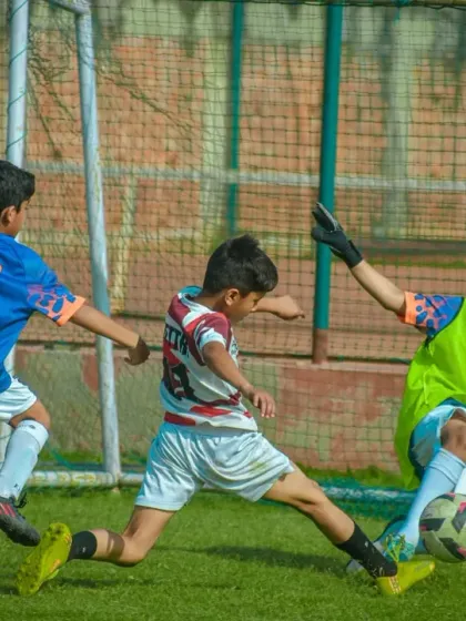 A goalkeeper makes a brave save at the feet of an attacker, a crucial moment that highlights courage and quick reflexes.