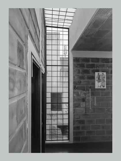 A black and white shot of a narrow light well, emphasizing the verticality and the grid of the window.