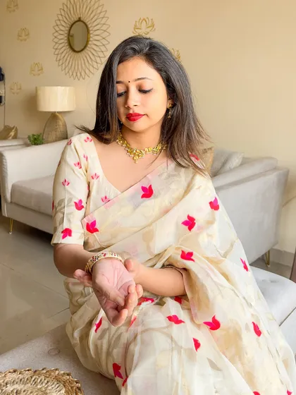 A detail shot focusing on the delicate gold jewelry against the off-white and red of the saree. It’s a very feminine and graceful look.