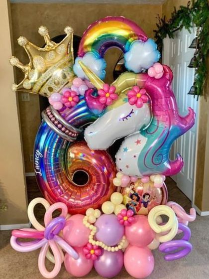 A magical unicorn and rainbow balloon bouquet for a 6th birthday. This elaborate creation is full of color and fantasy, featuring a large unicorn, a rainbow, a crown, and personalized number balloons.