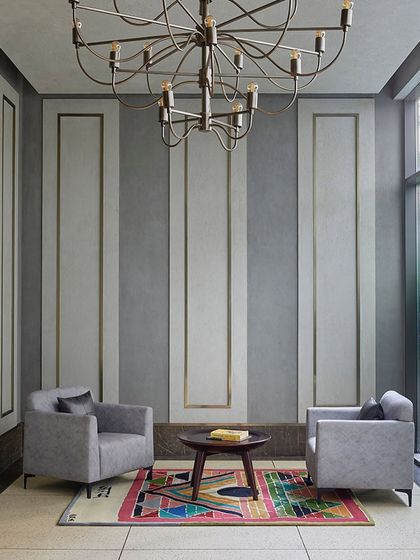 The entrance lobby for the theater and banquet has a subtle old-world charm, with textured concrete walls, elegant armchairs, and a striking modern chandelier.