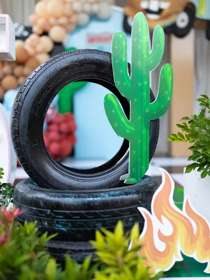 A creative use of real tires as props, stacked with a cactus cutout to evoke the desert landscape of Radiator Springs from the movie Cars.