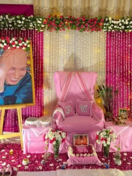 For this Guru Ji birthday event, I created a vibrant pink-themed decoration. The setup includes a portrait on an easel framed with red and white roses, a floor covered in fresh rose petals, and a decorated throne with 'Om' pillows.
