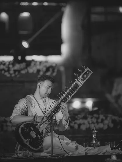 A black and white performance shot from Nepal. The contrast highlights the form and focus of the artist and instrument.