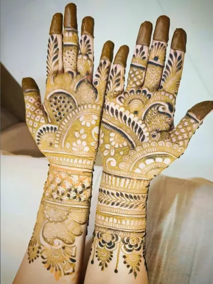This design features a prominent peacock on one palm and a lotus on the other, both surrounded by dense, traditional patterns that extend up the arm.