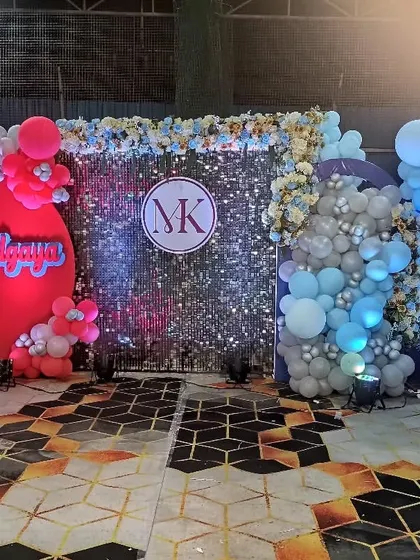 A combined pre-wedding party for the bride and groom's families. The decor features a central sequin wall with a custom monogram and two balloon arches in different colors.