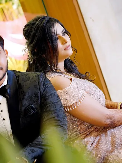 A stylish, candid-style portrait of the couple at their engagement. The foreground blur adds an intimate, "fly-on-the-wall" perspective.